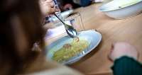 Person isst Nudeln mit Soße an einem Tisch.