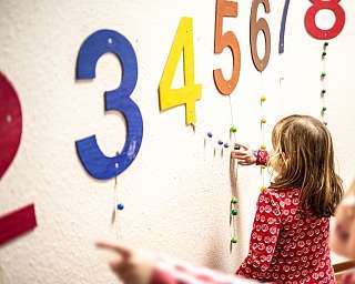 Ein Kind interagiert mit bunten Zahlen an einer Wand.