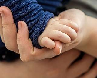 Ein Erwachsener hält die Hand eines kleinen Kindes.
